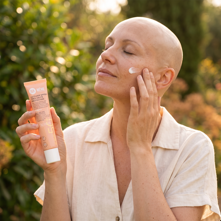 Frau ohne Haare trägt die MÊME Sonnencreme LSF 50+ im warmen Sonnenlicht auf